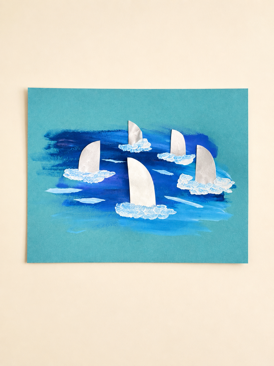 Preschool shark fin ocean art with white paper fins, blue painted water, and white wave details